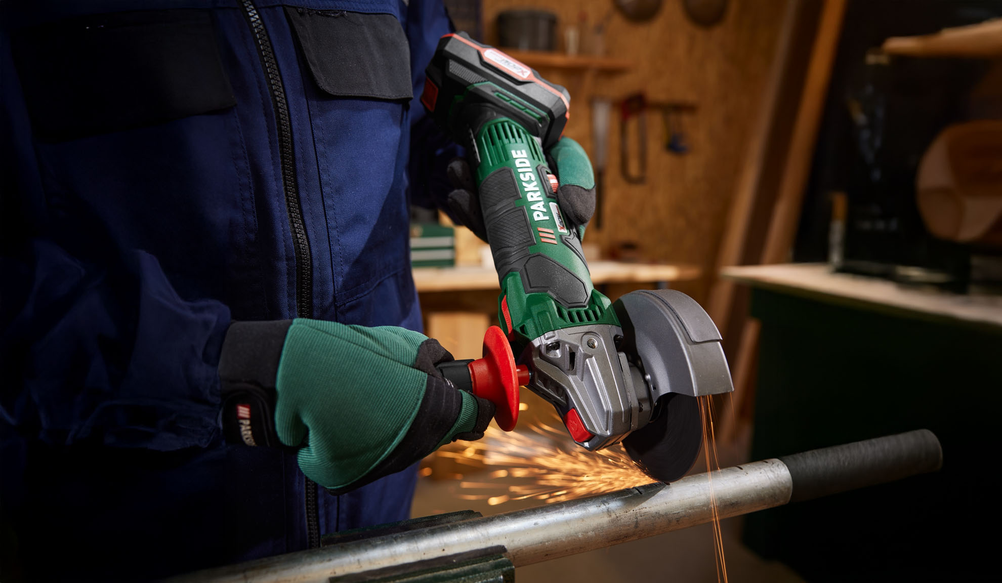 A worker uses a Parkside angle grinder to cut a metal pipe.