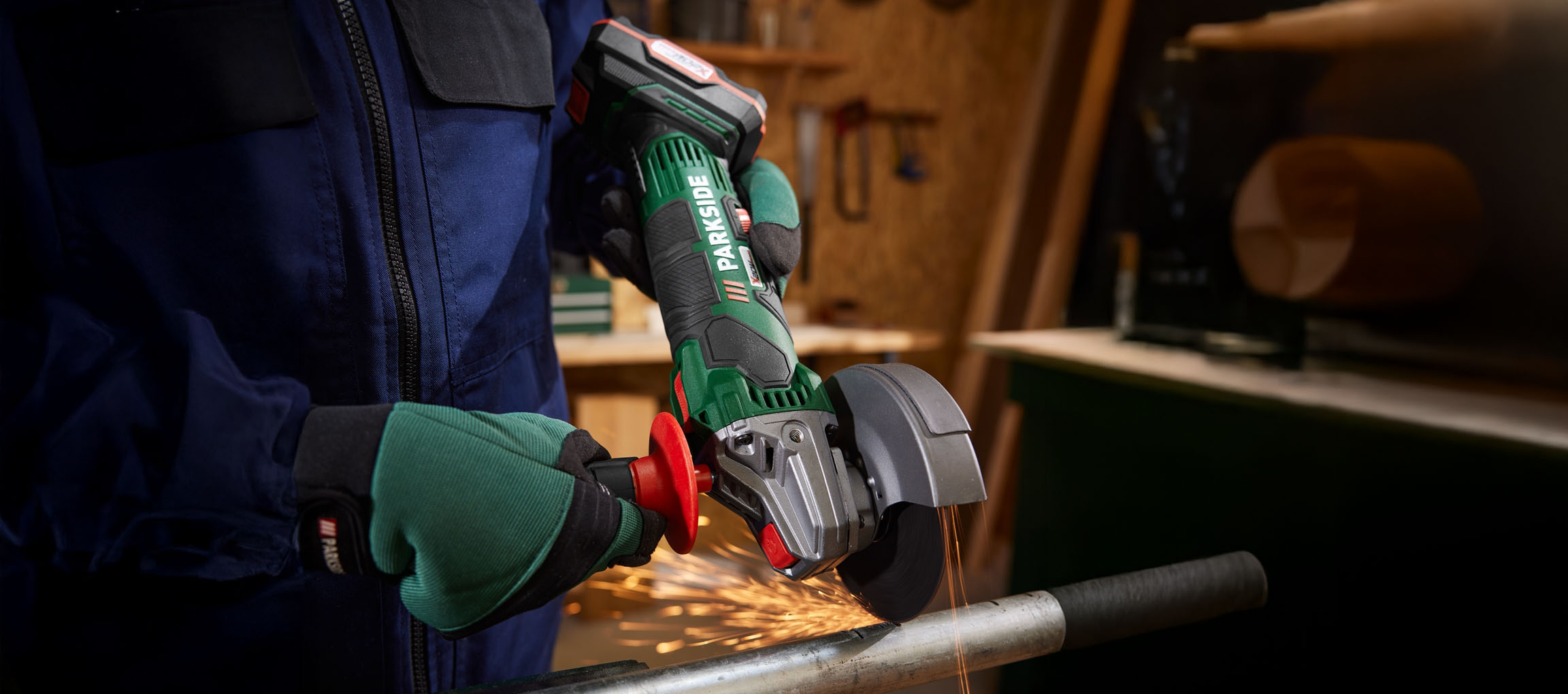 A worker uses a Parkside angle grinder to cut a metal pipe.