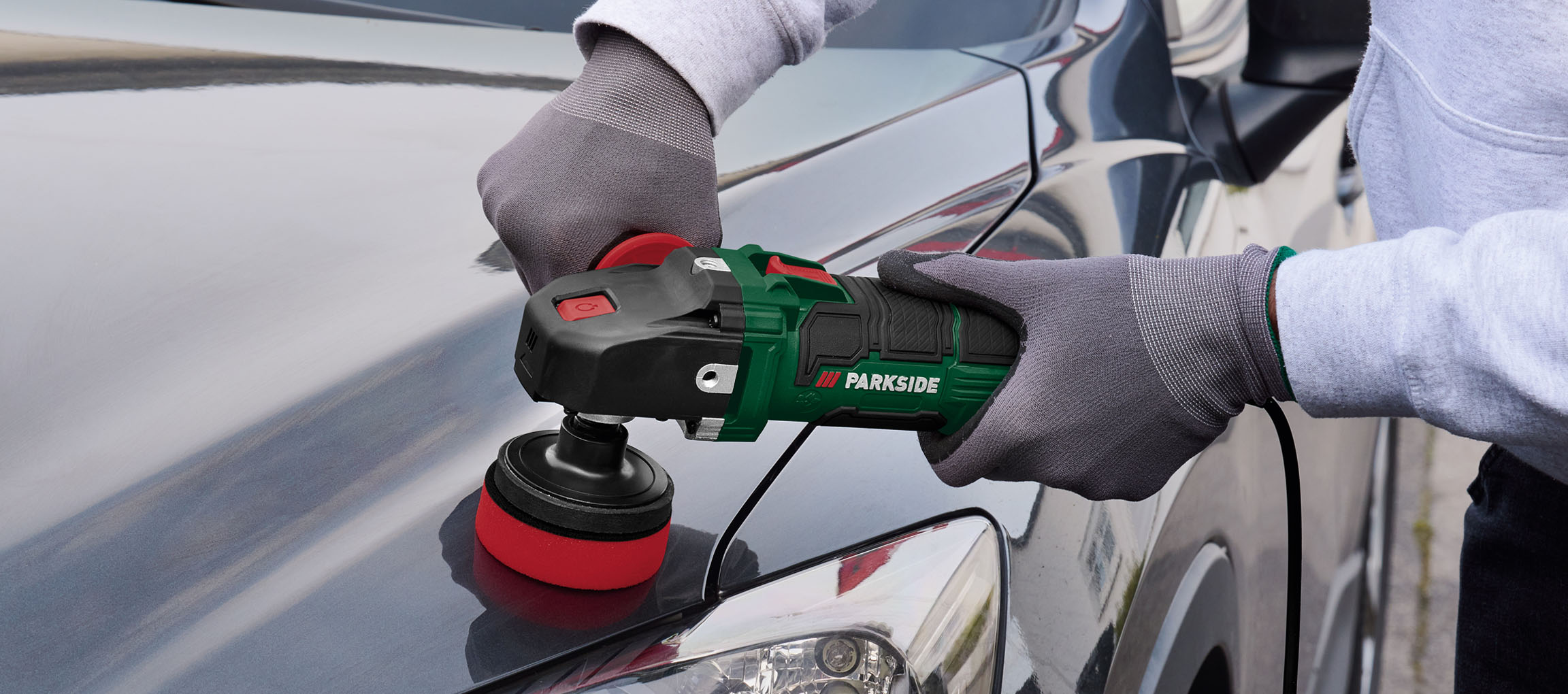 A person uses a Parkside polisher to buff a car.
