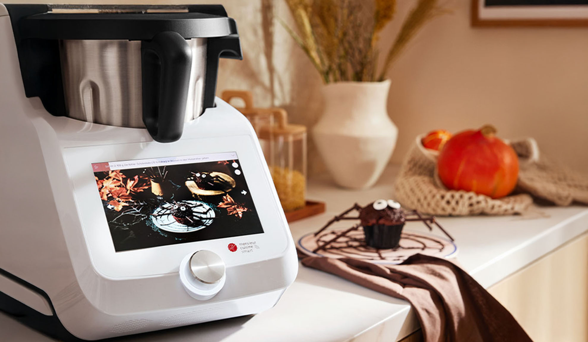 Kitchen machine with touchscreen, displaying Halloween recipes, on a kitchen counter.
