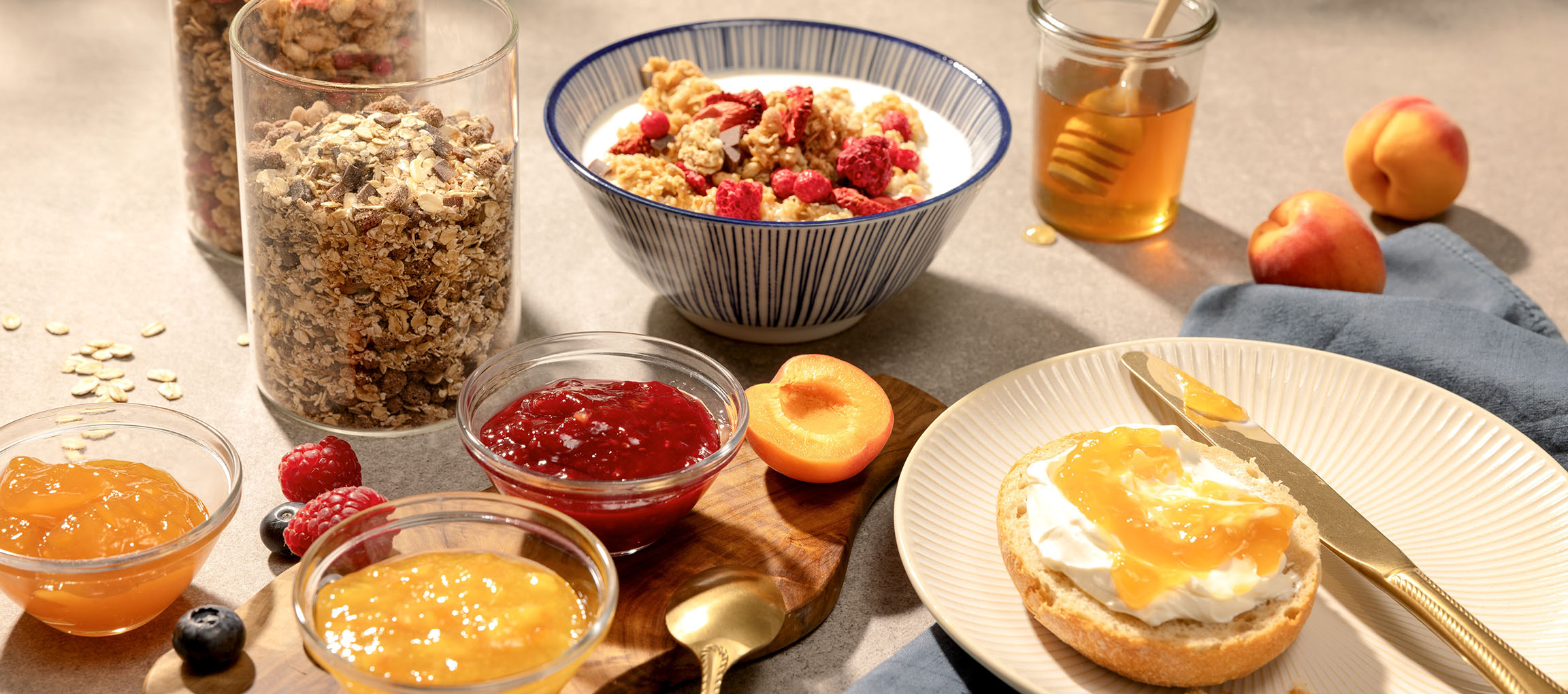Breakfast with muesli, jam, honey, and bread with cream cheese and jam.
