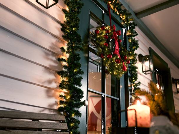 Christmas wreath and garland with lights on the door and wall.