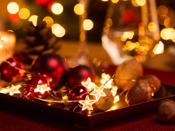 Christmas decorations with red baubles, star-shaped fairy lights, and hazelnuts on a tray.