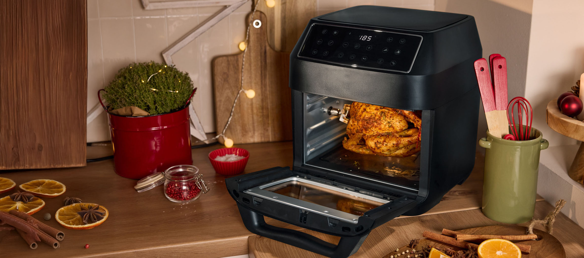 Air fryer with roasted chicken in a Christmas-decorated kitchen.