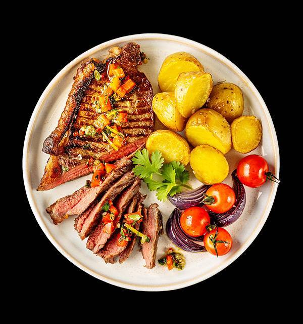 Grilled steak with salsa, sliced steak, roasted potatoes, cherry tomatoes, and red onion.