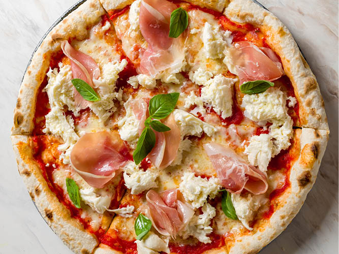 A delicious prosciutto and mozzarella pizza with fresh basil.