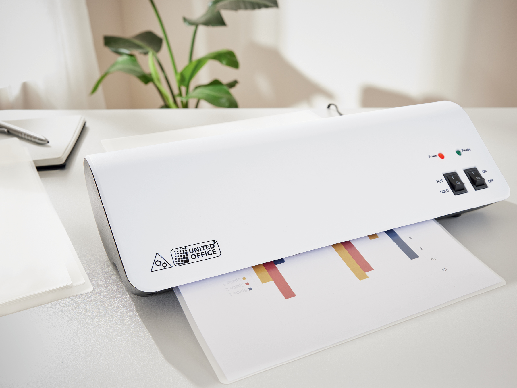 A United Office laminator is shown laminating a bar chart on a white desk.