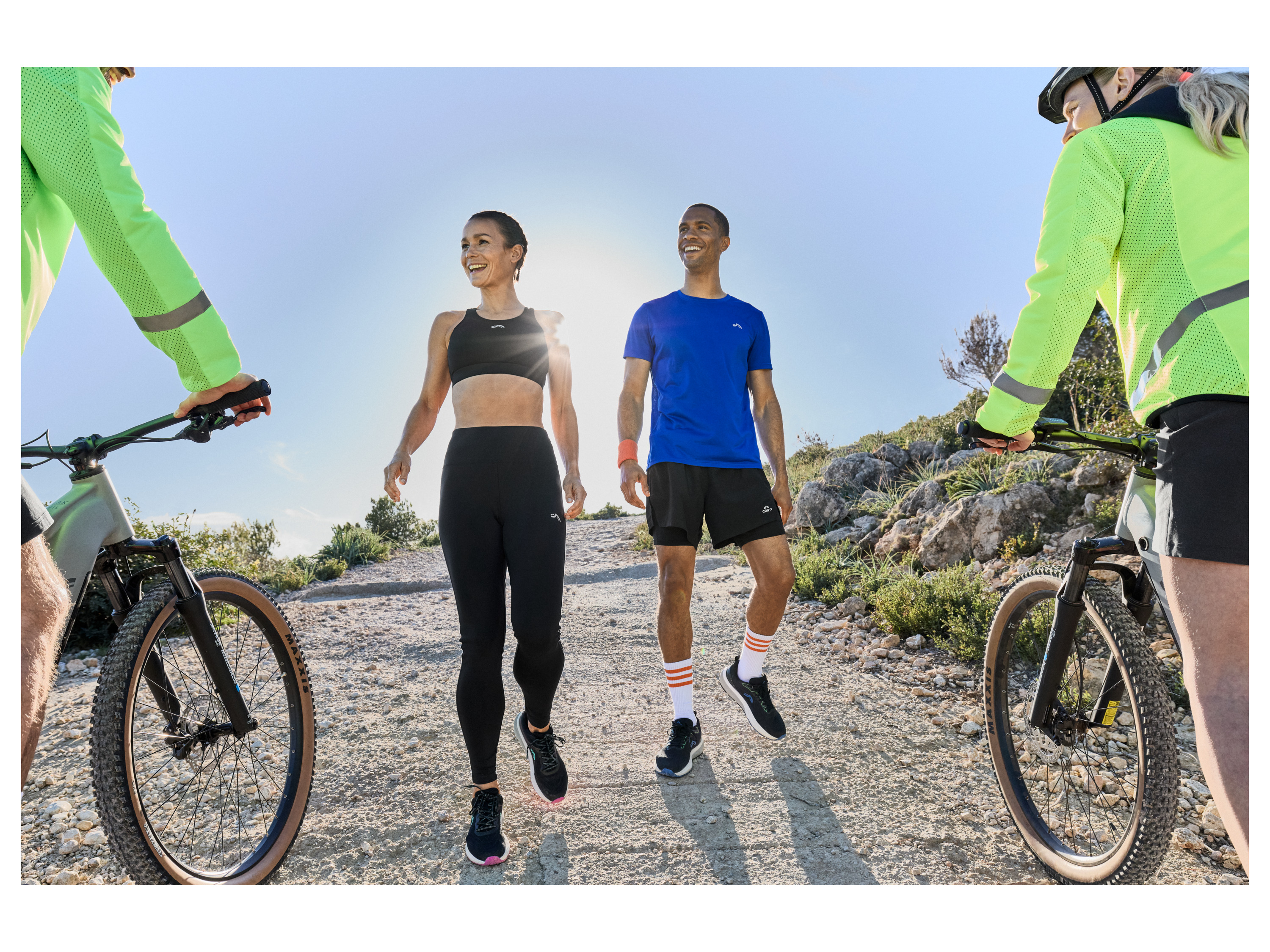 Three adults enjoy an outdoor workout, two running and one cycling, wearing Karrimor sportswear.