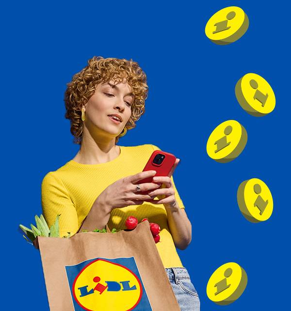 Woman with curly hair holding a red phone, carrying a grocery bag with fresh produce.