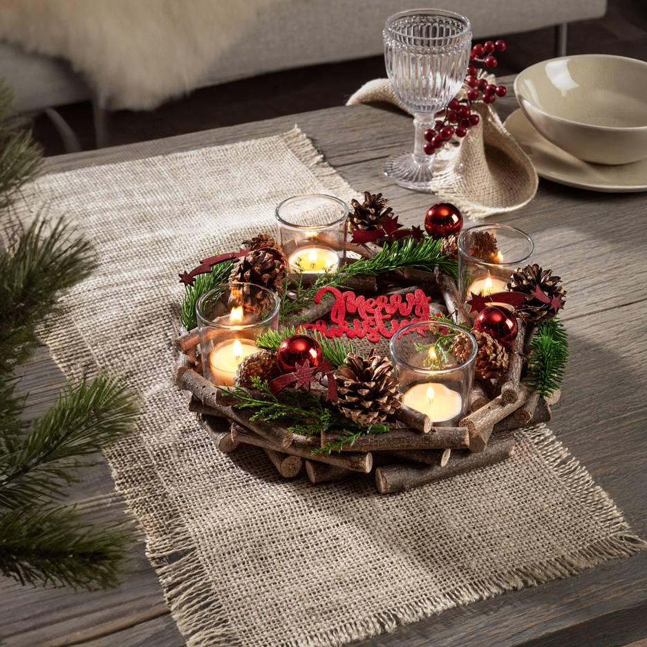 Christmas table decoration with candles, pine cones, and fir branches on a rustic wooden tray and jute runner.