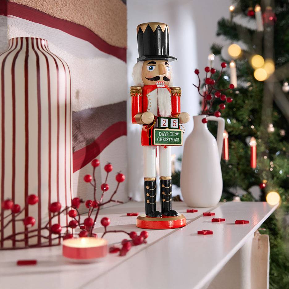 Nutcracker with advent calendar, vases, and Christmas decorations on a shelf.