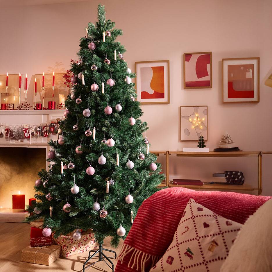 Christmas tree with pink and silver baubles in a cozy living room.