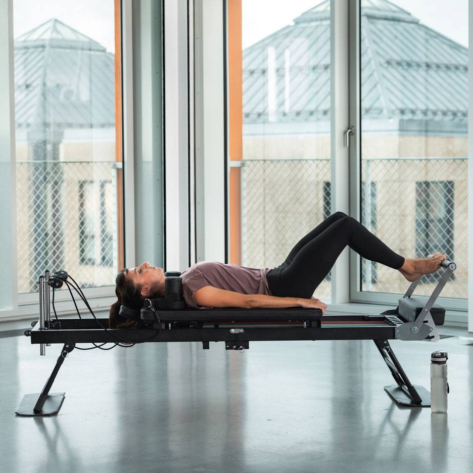 Woman doing Pilates exercise on a reformer machine.