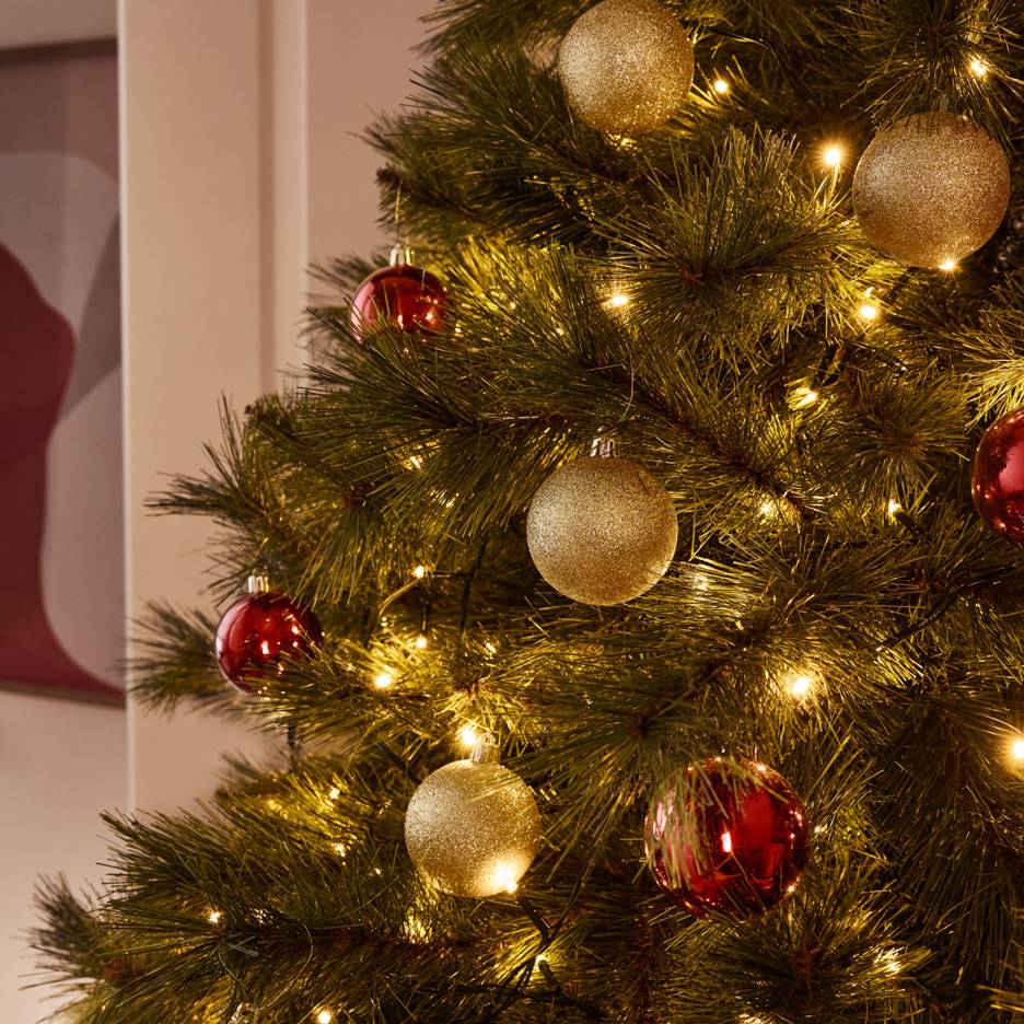 Christmas tree adorned with glittery gold and red baubles and warm string lights.