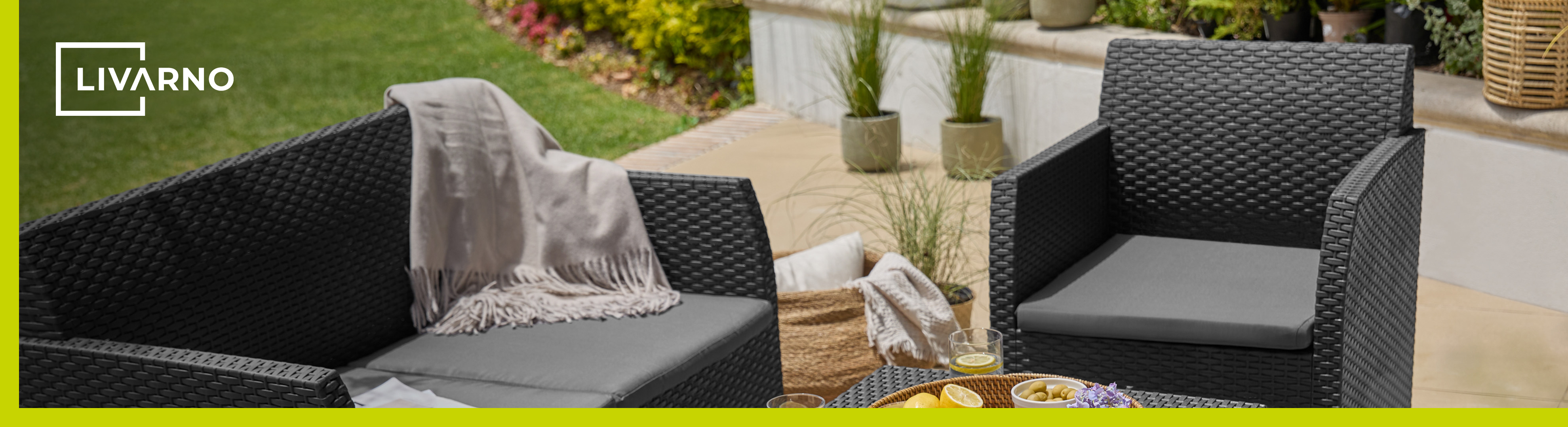 Outdoor patio furniture set with black woven chairs, grey cushions, and a blanket.