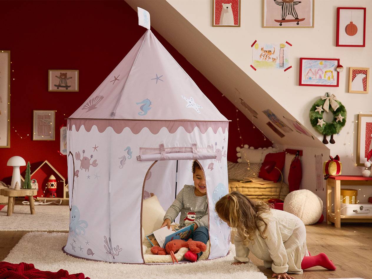 Two children playing with a sea-themed play tent in a child's room with Christmas decorations.
