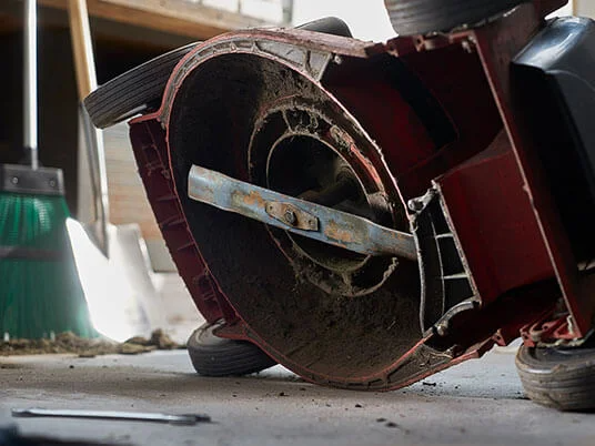 Dirty lawnmower upside down, blade visible