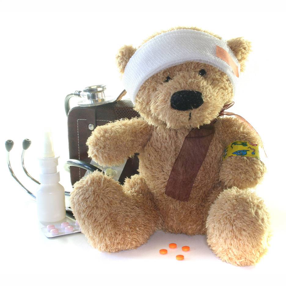 Injured teddy bear with head bandage, medical bag, stethoscope, and medicines.