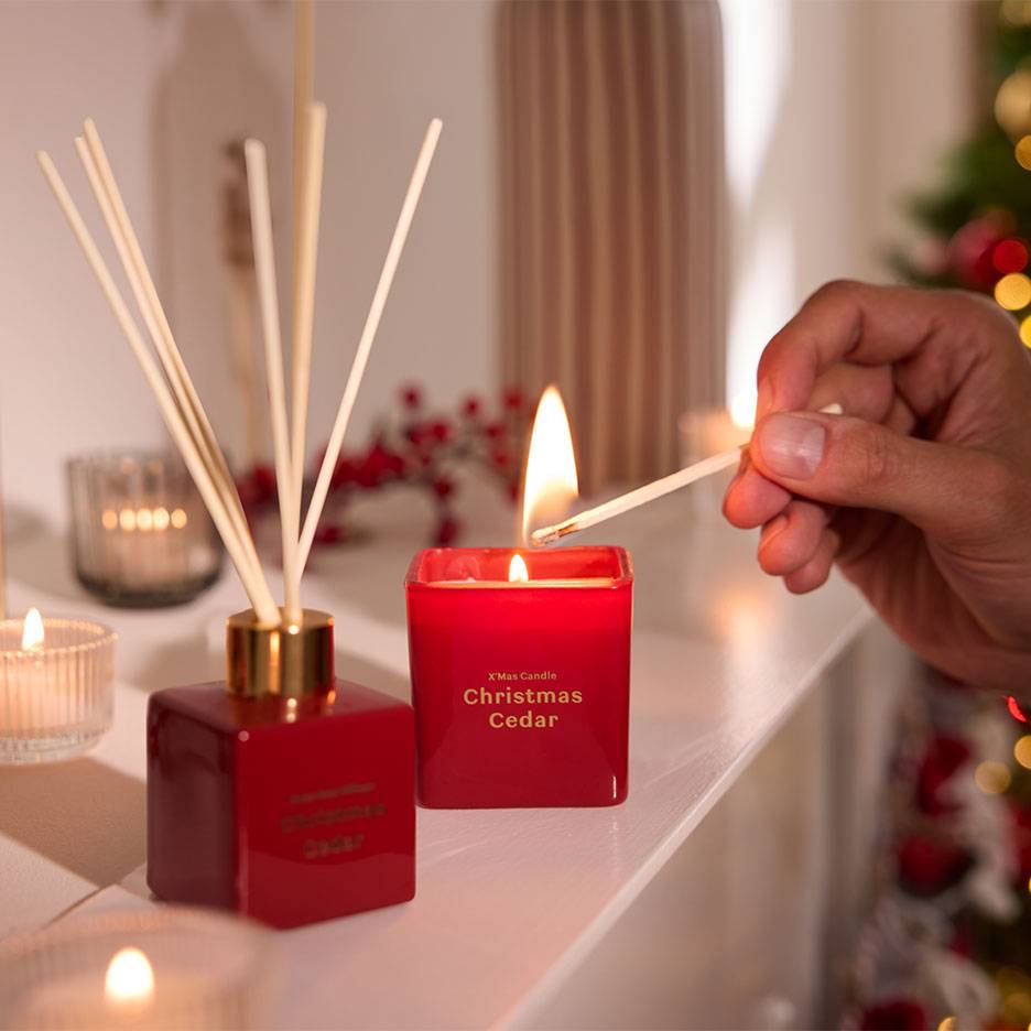 Red Christmas Cedar diffuser and candle being lit with a match.