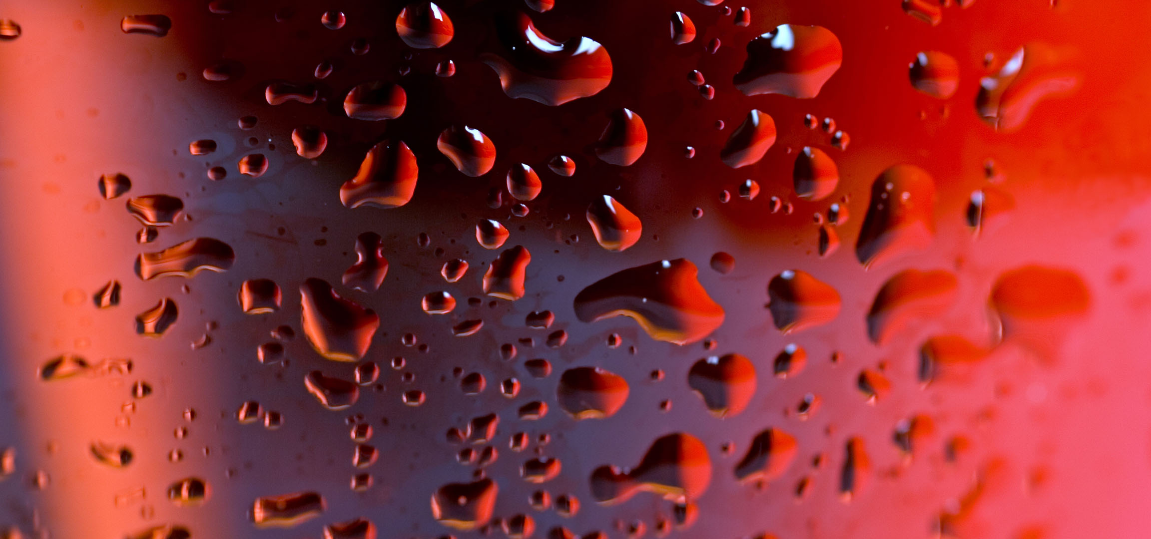Red water droplets on a surface with a blurred background