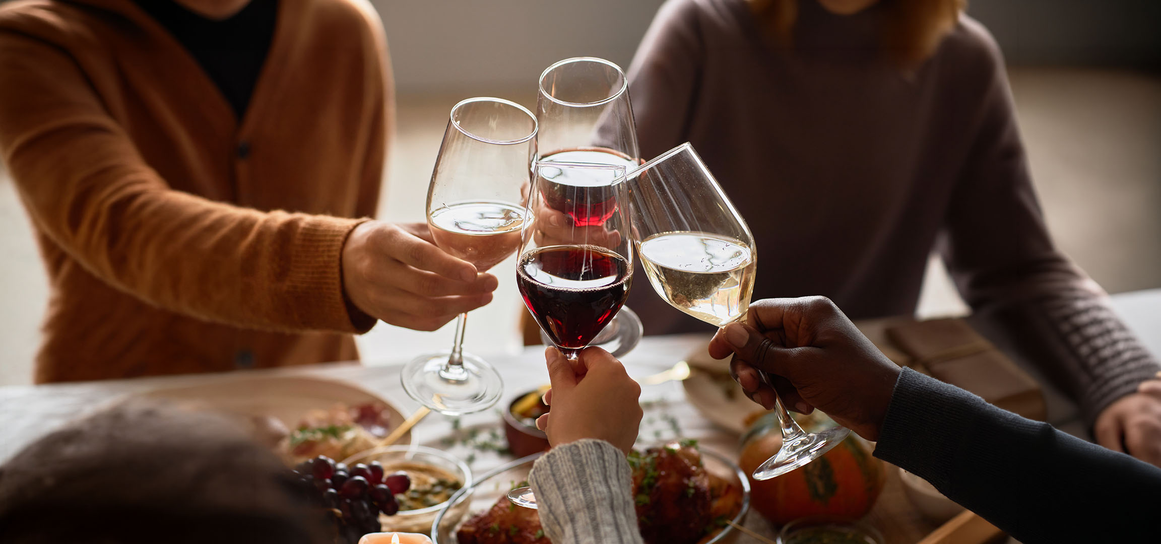 People toasting with glasses of red and white wine.