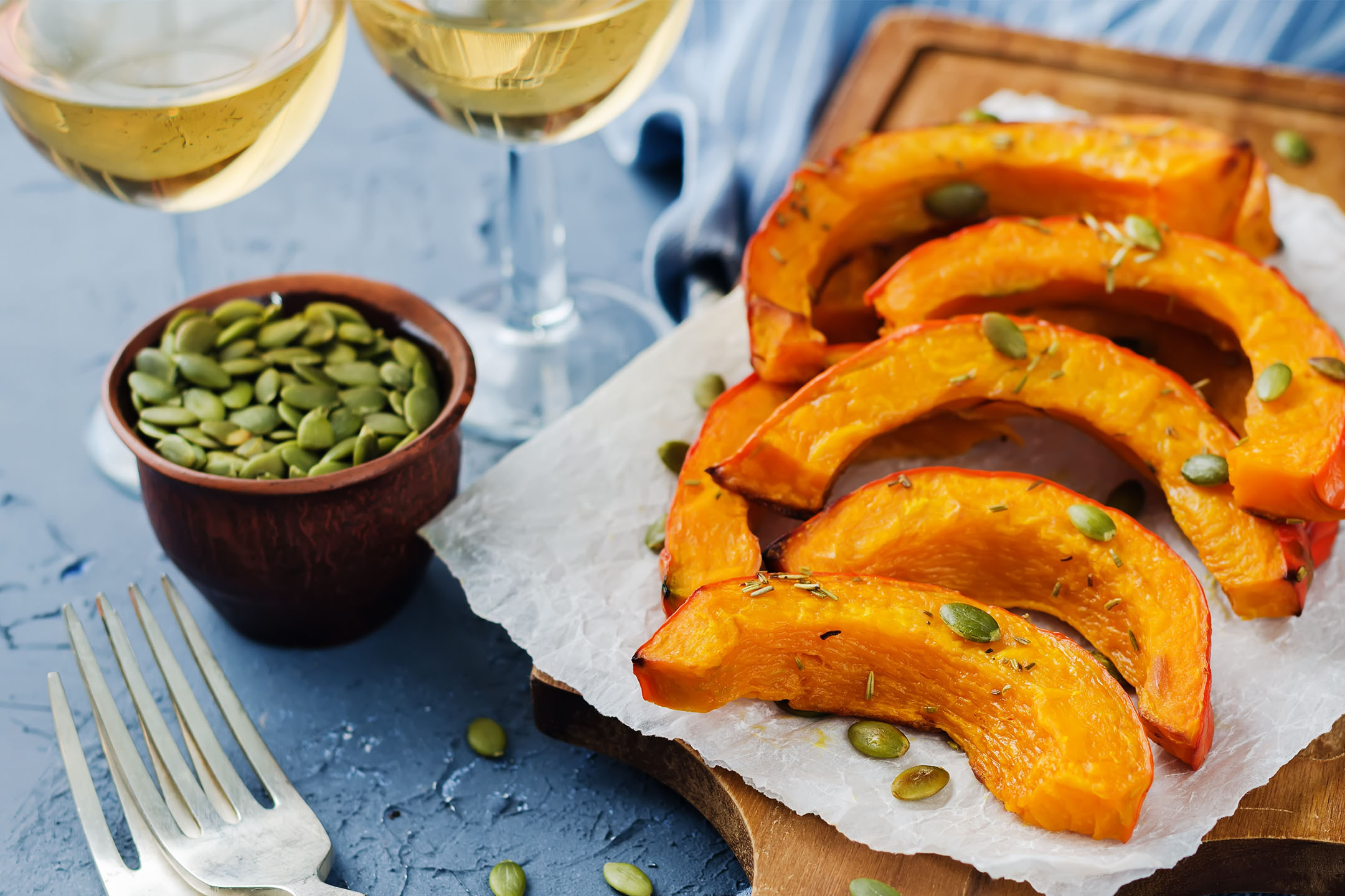 Roasted pumpkin wedges with pumpkin seeds and rosemary, served with white wine.