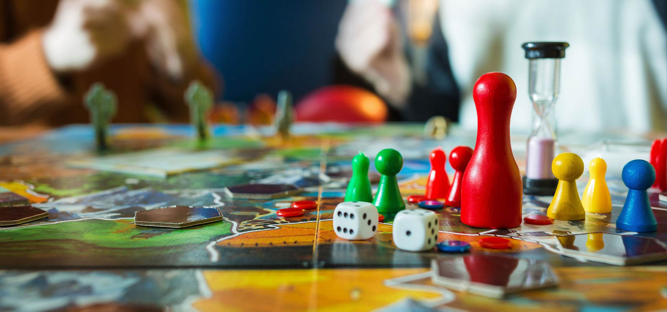 Colorful board game pieces, including red, green, yellow, and blue pawns, with dice.