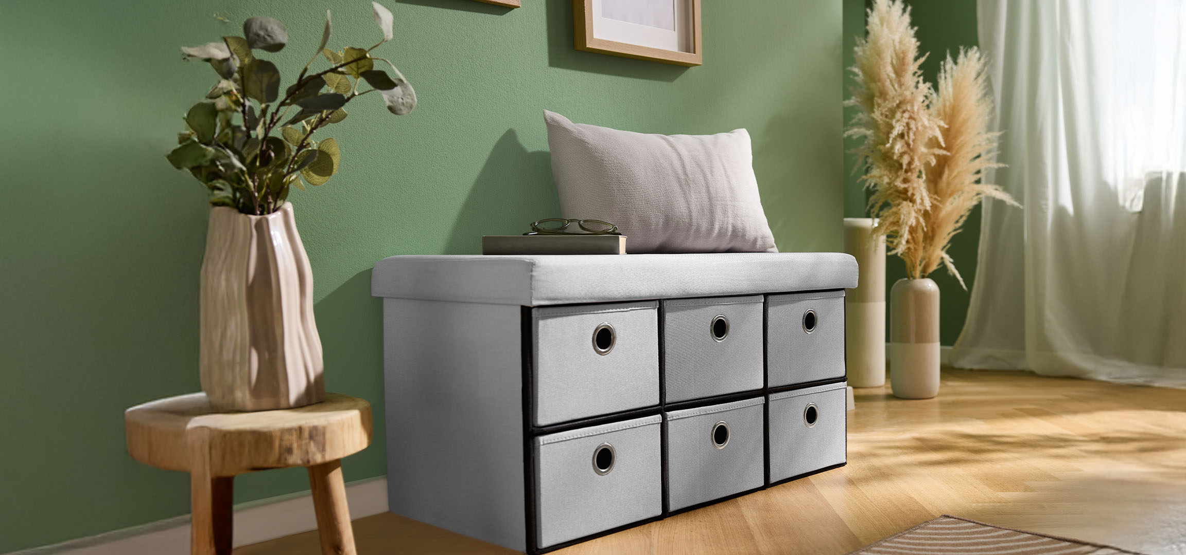 Grey storage bench with drawers in a room with green walls and a wooden floor.