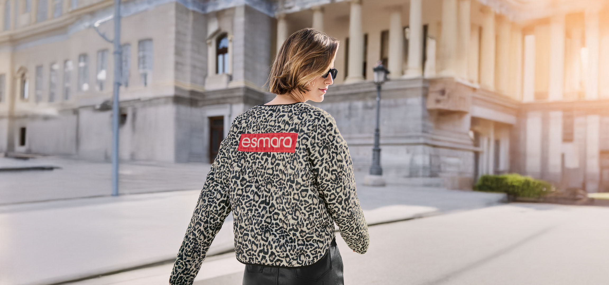 Woman in an Esmara leopard jacket, sunglasses, on an urban street.