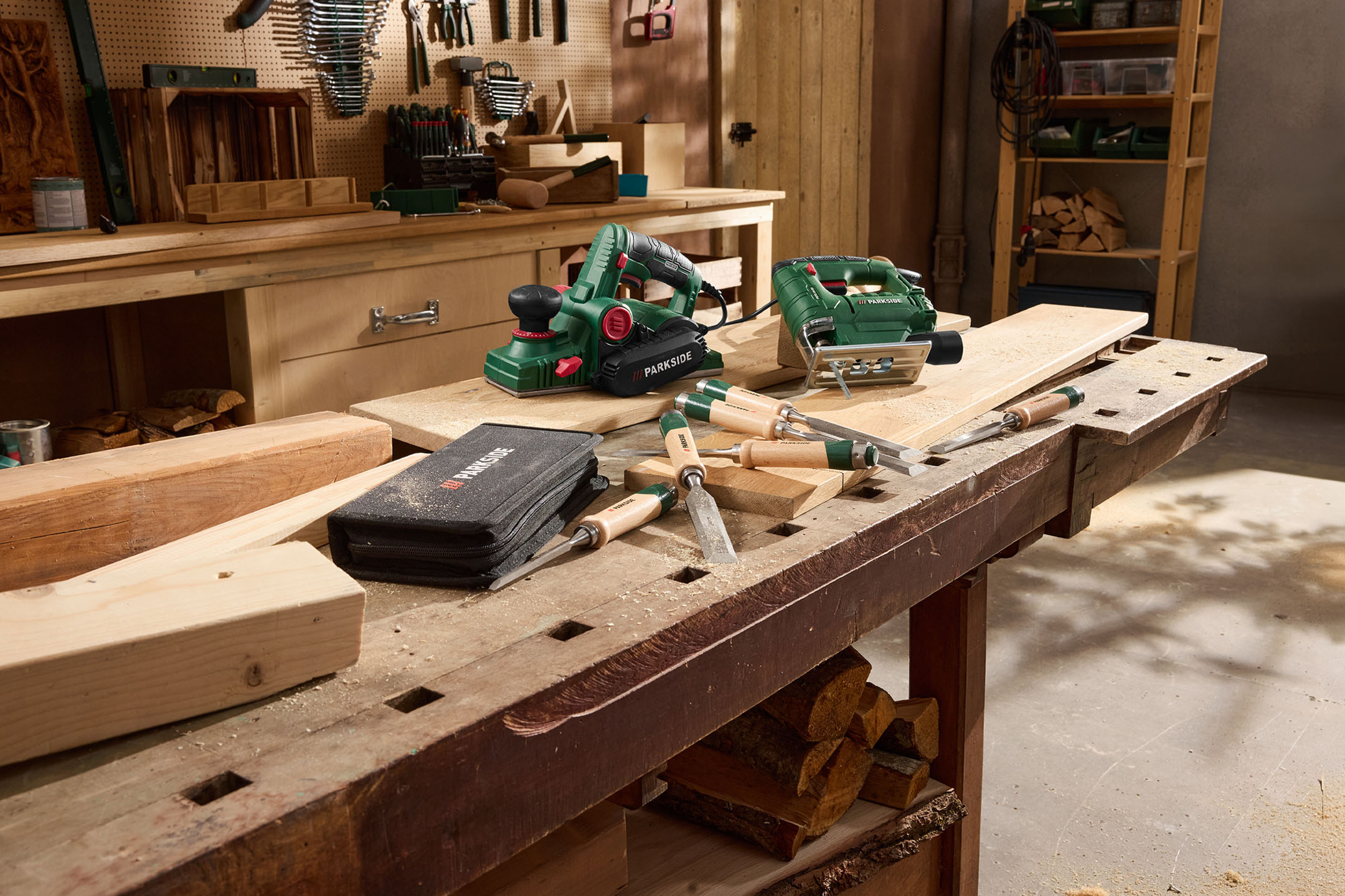 Power tools and wood chisels on a wooden workbench, with sawdust.
