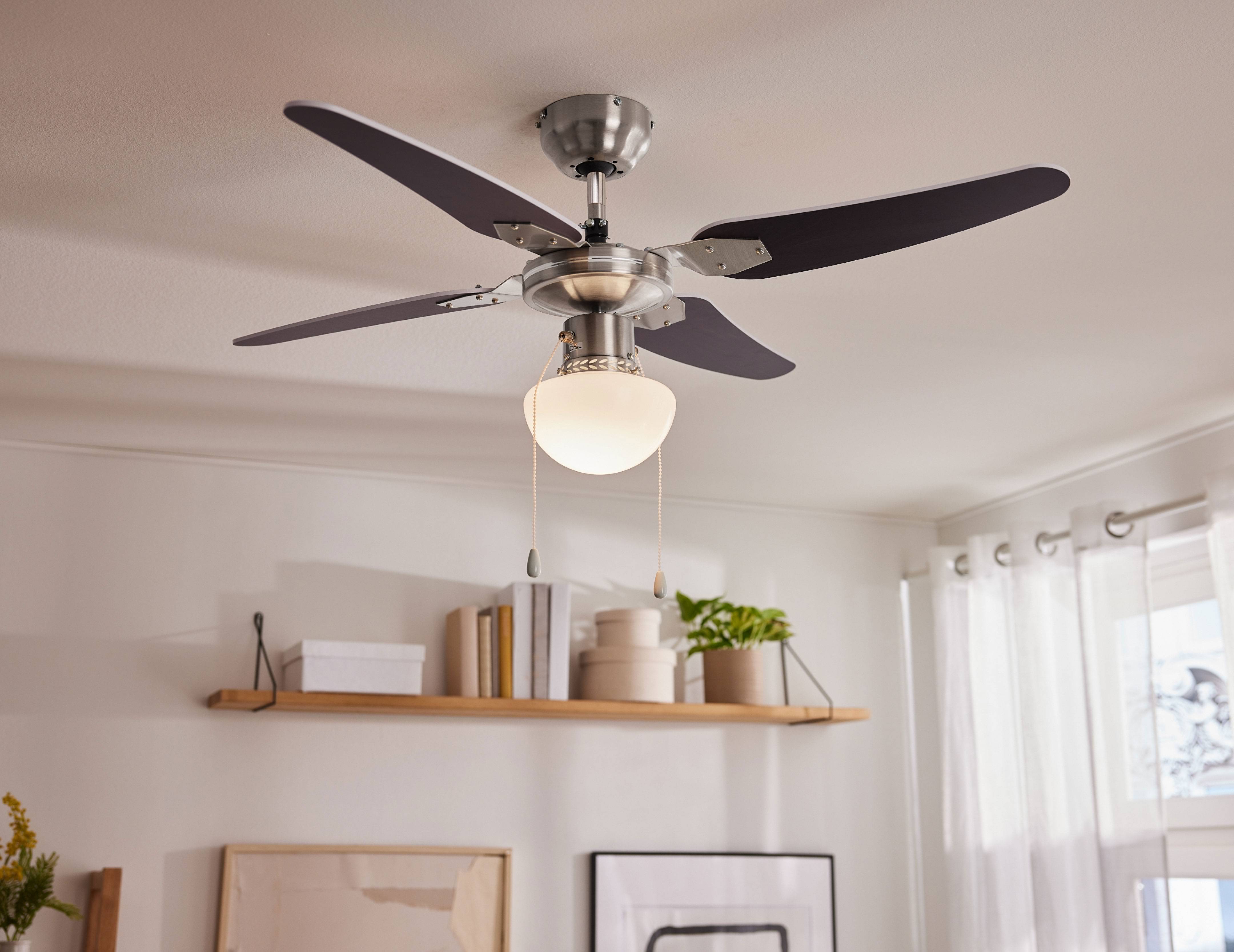 Ceiling fan with light in a modern living room with a shelf and window.