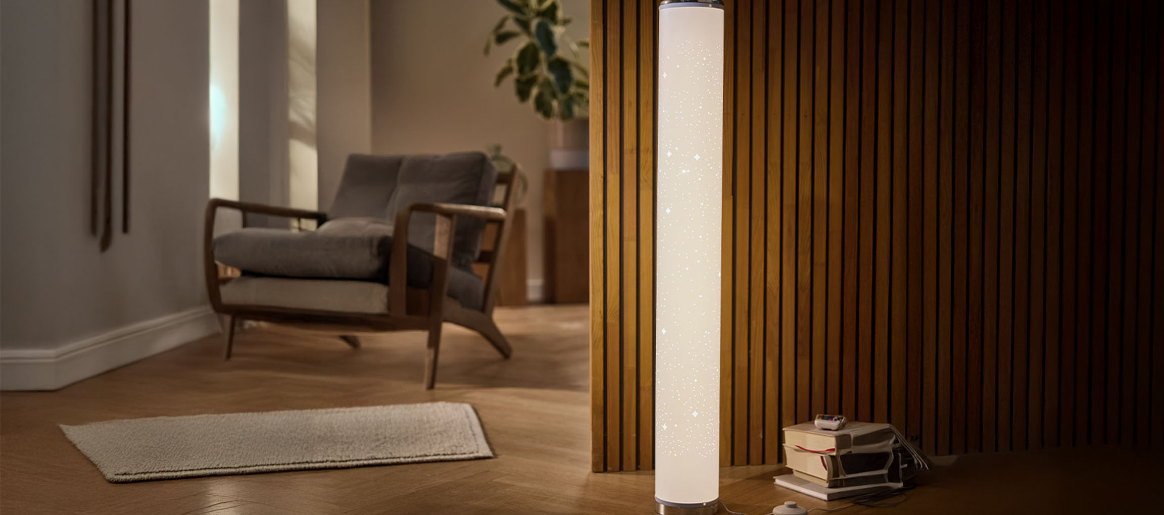 Cylindrical floor lamp with a star pattern, next to a wooden slatted wall and an armchair.