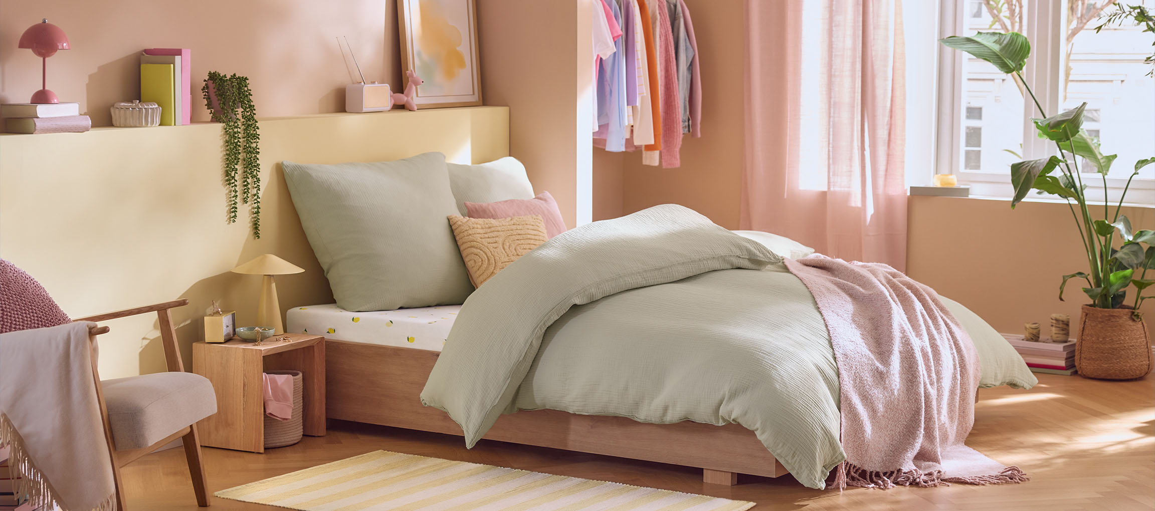 Bedroom with wooden bed, mint green bedding, cushions, and a pink throw.