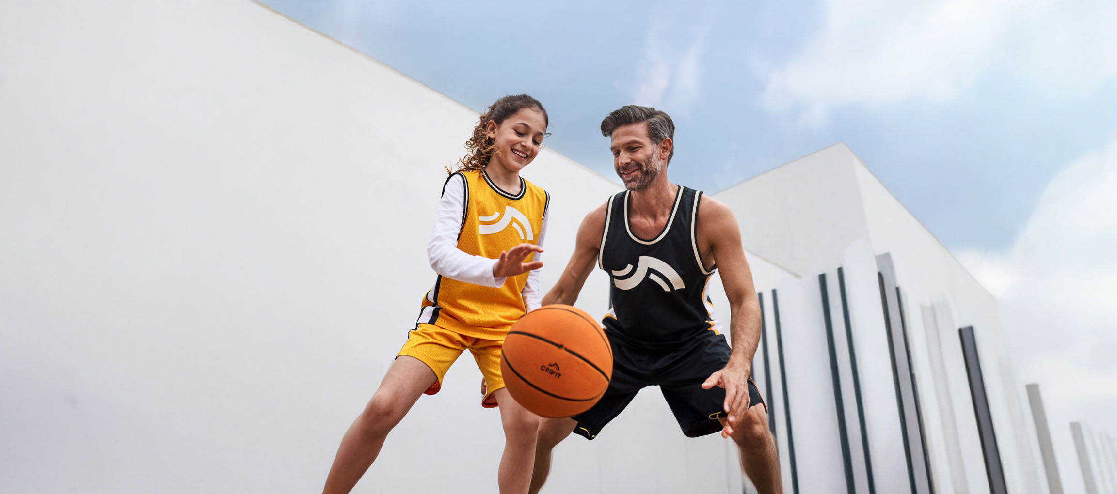 Father and daughter playing basketball in basketball outfits and with a ball