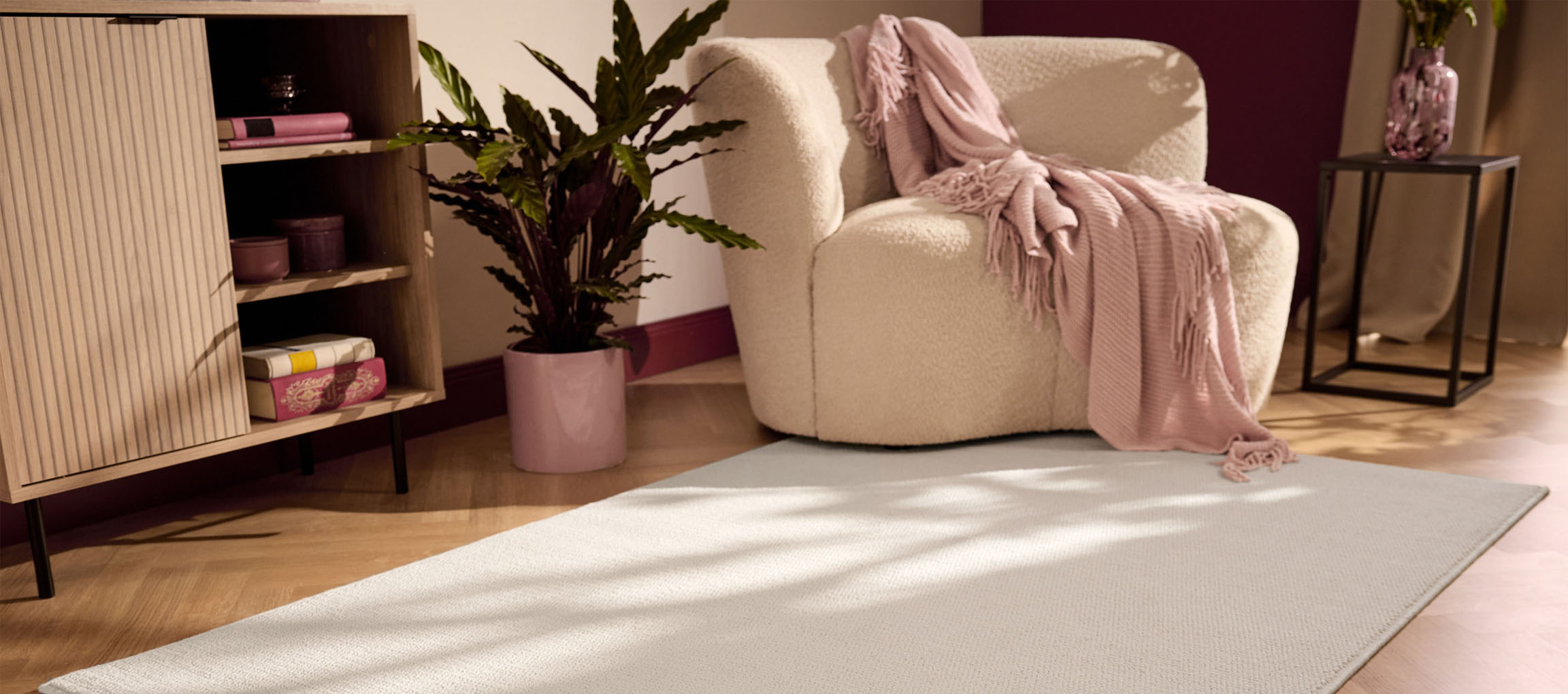 A light rug on a wooden floor, with a beige armchair and a wooden cabinet.