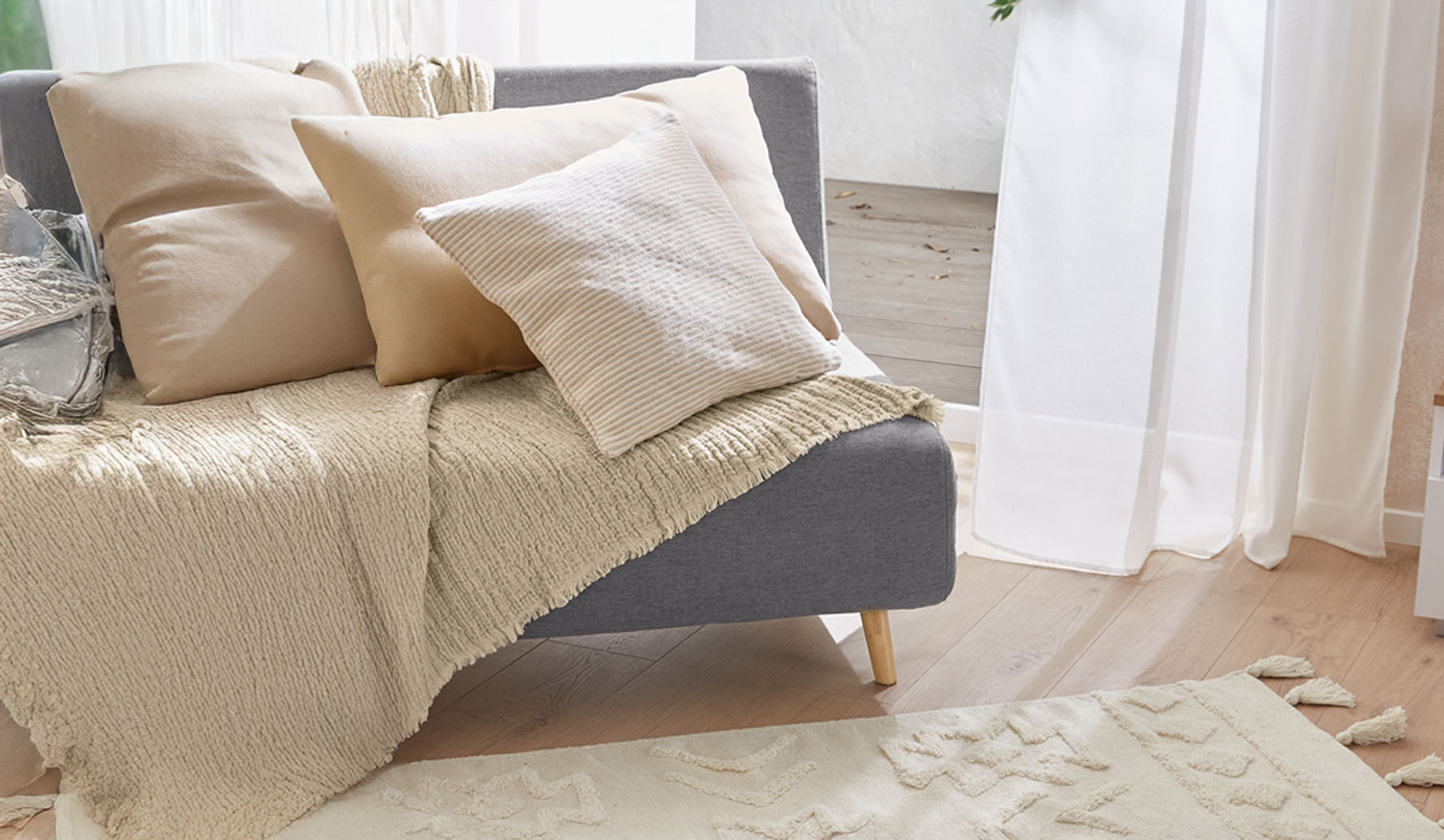 Gray sofa with beige pillows and textured throw in a bright living room.