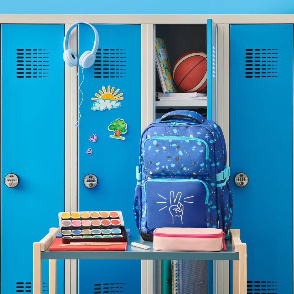 Blue backpack with a peace sign, watercolors, and headphones in front of school lockers.