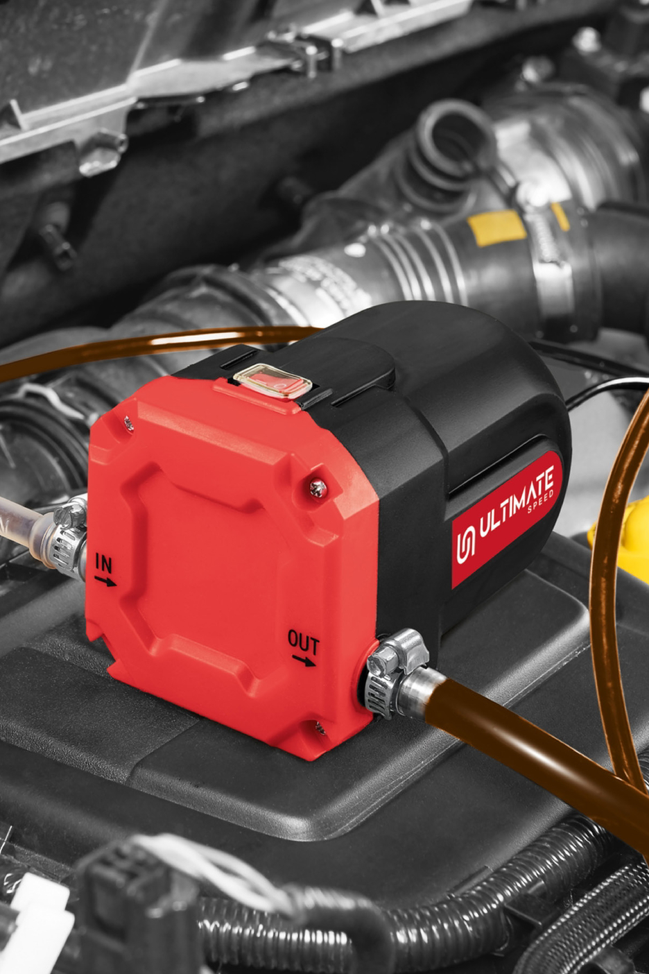 A red and black Ultimate Speed oil extraction pump connected to hoses in a car engine.