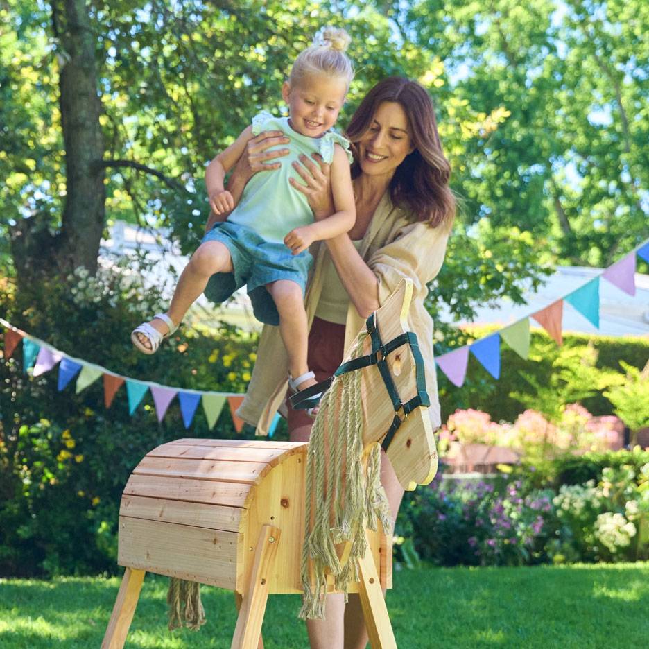 Woman and child with a wooden rocking horse in a garden with bunting.